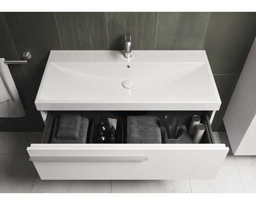 Meuble sous-lavabo avec tiroir ouvert, serviettes et accessoires de salle de bain