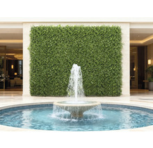 Dekorative grüne Wand mit einem Springbrunnen im Vordergrund
