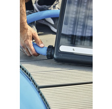 Une personne raccorde un tuyau bleu à un absorbeur solaire.