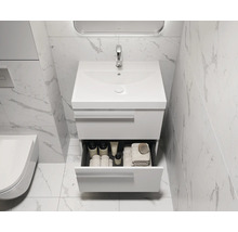 Salle de bains moderne avec meuble sous-lavabo et tiroir ouvert contenant des articles de toilette.