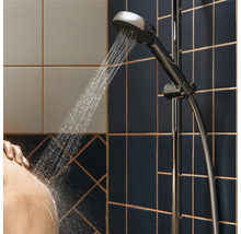 Pomme de douche avec eau courante dans une salle de bain avec murs carrelés.