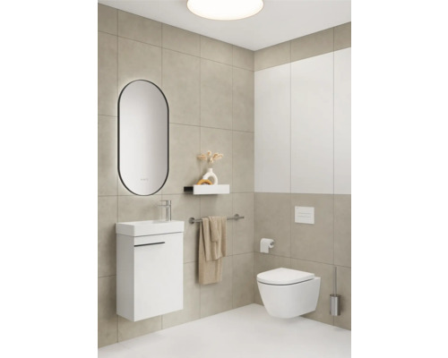 Salle de bains lumineuse avec lavabo, miroir, WC suspendu et porte-serviettes devant un mur carrelé