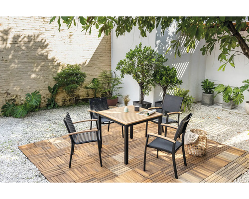 Quadratischer Gartentisch mit vier Stühlen auf Holzboden in einem Garten.