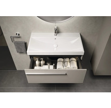 Waschtisch mit Schublade, Waschbecken, Handtüchern und Badartikeln in einem Badezimmer