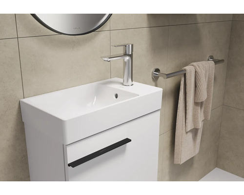 Waschtisch mit Armatur, Handtuch und Spiegel im Badezimmer