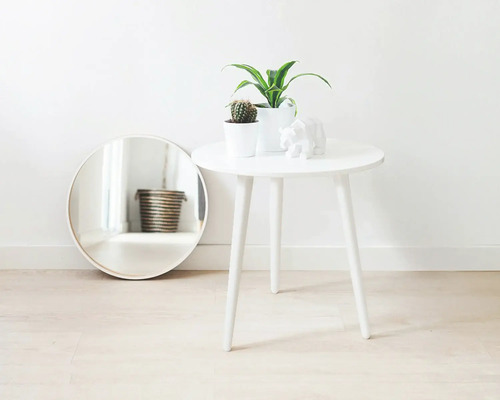 Scène décorative avec miroir rond, table d'appoint, plantes d'intérieur et sculpture