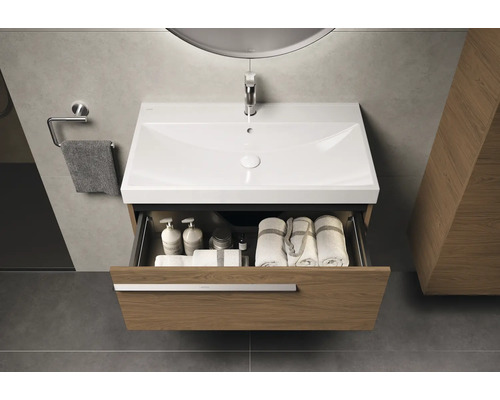 Meuble-lavabo avec tiroir ouvert dans la salle de bains, avec serviettes et produits de soin à l'intérieur