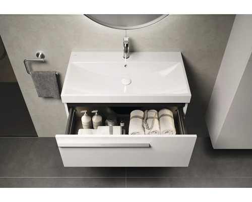 Meuble-lavabo avec tiroir ouvert, comprenant des serviettes et des produits de soin dans la salle de bain.