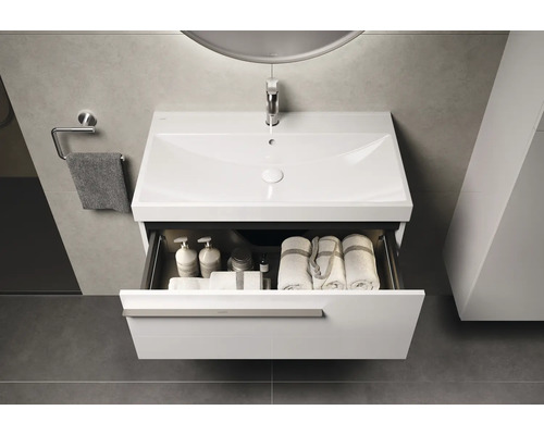 Meuble-lavabo avec tiroir ouvert, serviettes et produits de soins dans une salle de bain moderne