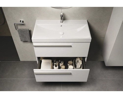 Meuble-lavabo avec tiroir ouvert, rempli de serviettes et d'accessoires de salle de bain, dans la salle de bain