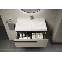 Meuble-lavabo de salle de bain avec tiroir, lavabo, serviette et robinetterie sous un miroir avec éclairage