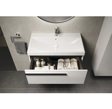 Meuble sous-lavabo avec tiroir ouvert, contenant des serviettes et des produits de soin
