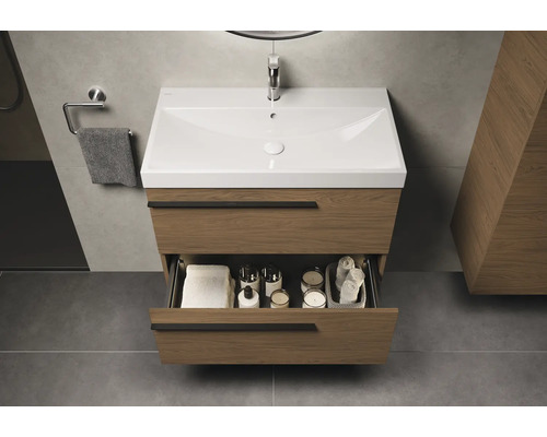 Meuble sous-lavabo avec tiroir ouvert, serviettes et accessoires de salle de bain