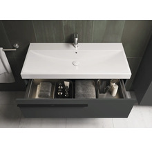 Meuble-lavabo avec tiroir ouvert contenant des serviettes et des articles de toilette