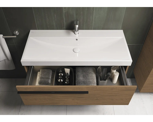 Meuble sous-vasque avec tiroir ouvert, équipé de serviettes et d'accessoires de salle de bain.