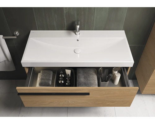 Meuble sous-lavabo avec tiroir ouvert, serviettes et accessoires de salle de bain