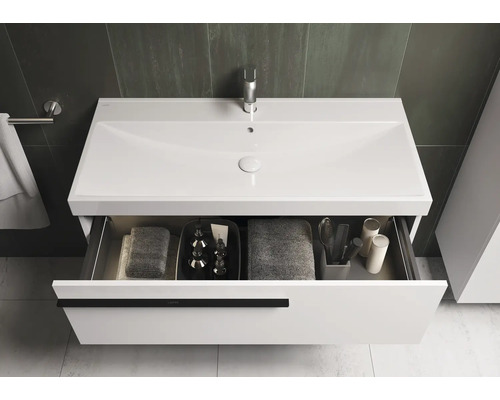 Meuble-lavabo avec tiroir ouvert, comprenant des serviettes et des accessoires de salle de bain