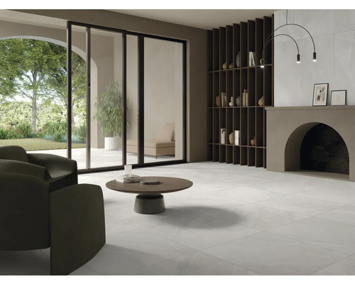 Heller Wohnraum mit Fliesenboden, Sessel, Couchtisch und Regal