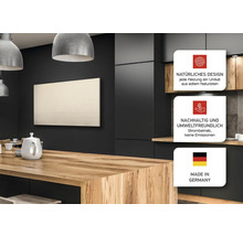 Nahaufnahme eines Raumes mit einem an der Wand montierten Heizpaneel, das über einem Holztisch hängt, mit den Siegeln natürliches Design, nachhaltig und umweltfreundlich sowie hergestellt in Deutschland.