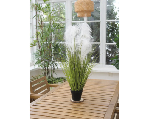 Dekorative Kunstpflanze mit Federn in einem Topf auf einem Holztisch