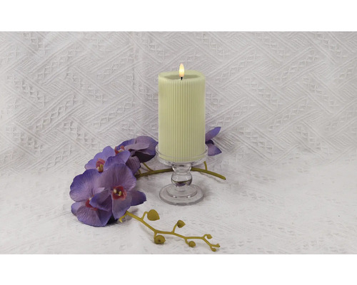 Bougie décorative à rainures sur un support en verre avec une orchidée violette