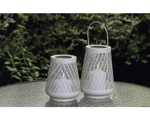 Zwei weiße Gartenlaternen mit Muster auf einem Tisch