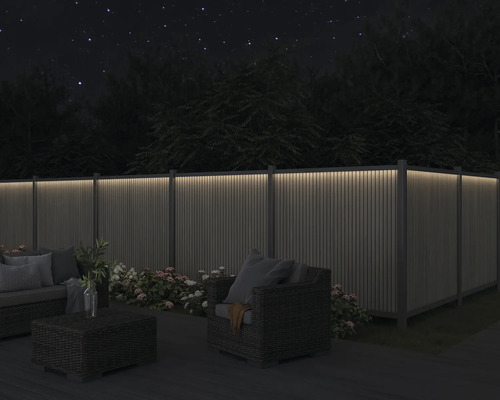 Garten mit beleuchtetem Zaun, Sitzgruppe und Blumen bei Nacht