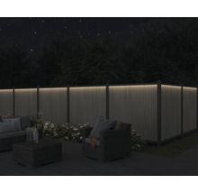 Gartenmöbel-Set auf einer Terrasse mit beleuchtetem Holzzaun bei Nacht