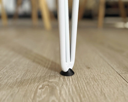 Gros plan sur un pied de table blanc avec protection de sol sur un plancher en bois.