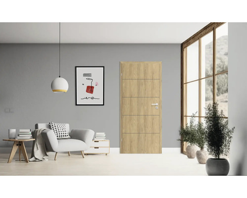 Wohnzimmer mit Holztür, Sessel, Beistelltisch, Kommode, Lampe, Fenster und Zimmerpflanzen für eine helle und freundliche Atmosphäre.