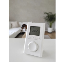 Weißer elektronischer Raumthermostat mit digitaler Anzeige auf einem Tisch