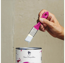 Eine Hand hält einen Pinsel mit Farbe über eine Farbdose der Marke Miss Pompadour.