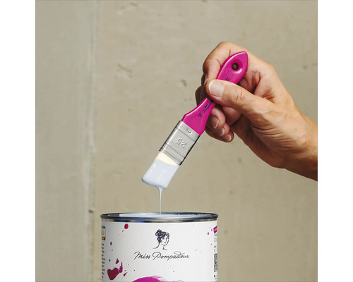 Eine Hand hält einen Pinsel mit Farbe über eine Farbdose der Marke Miss Pompadour.