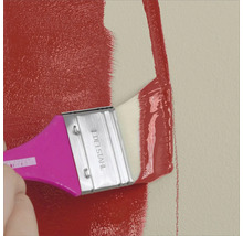 Eine Wand wird mit einem Pinsel und roter Farbe gestrichen.