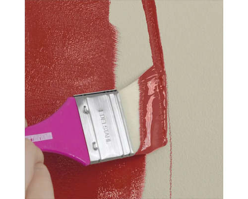 Eine Wand wird mit einem Pinsel und roter Farbe gestrichen.