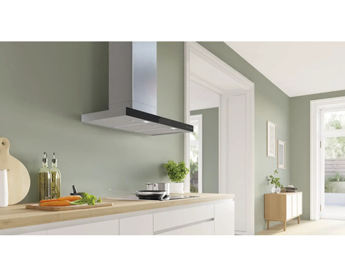 Scène de cuisine avec hotte aspirante, plaque de cuisson, plan de travail et ustensiles de cuisine dans une cuisine lumineuse.