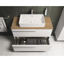 Modernes Badezimmer mit weißem Waschtisch, Holzplatte und geöffneter Schublade zur Aufbewahrung von Badutensilien.