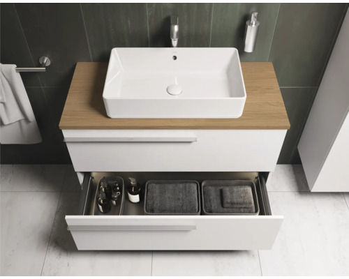 Modernes Badezimmer mit weißem Waschtisch, Holzplatte und geöffneter Schublade zur Aufbewahrung von Badutensilien.