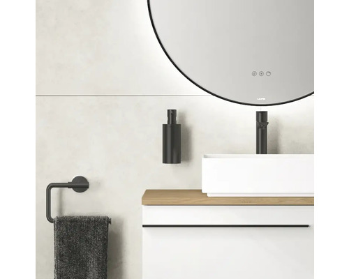 Salle de bain avec miroir rond, lavabo, robinet, distributeur de savon et porte-serviettes