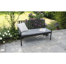 Banc de jardin avec coussin et magazine dans le jardin