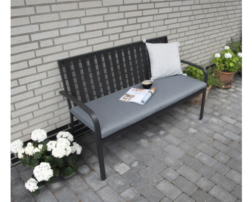 Banc de jardin avec coussin et revêtement devant un mur