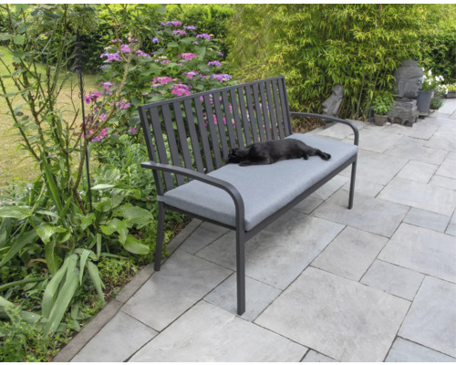 Banc de jardin avec revêtement gris et chat couché dans le jardin.