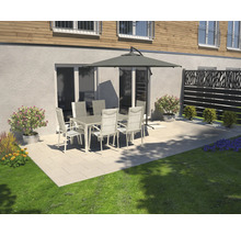 Scène de terrasse avec table de jardin, chaises et parasol devant un mur de maison