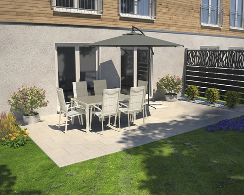 Scène de terrasse avec table de jardin, chaises et parasol devant un mur de maison