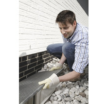 Ein Mann installiert einen Lichtschachtrost an einem Haus