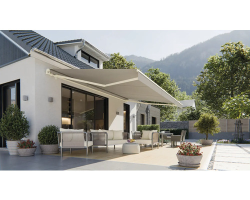Hausfassade mit ausgefahrener Markise und Gartenmöbeln auf der Terrasse.