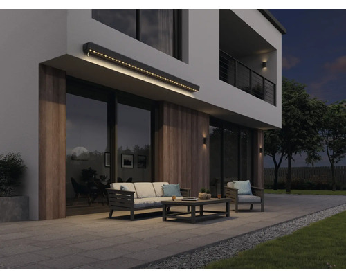 Façade de maison moderne avec store éclairé, mobilier de jardin et terrasse