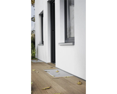 Extérieur d'une maison avec des fenêtres et une porte, ainsi qu'une terrasse en bois avec un saute-de-loup