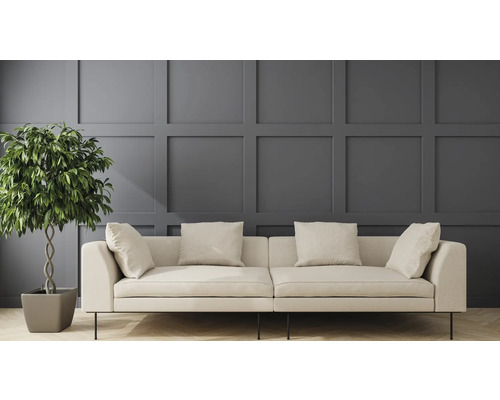 Canapé clair avec coussins et plante d'intérieur devant un panneau mural