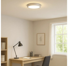 Beleuchtetes Arbeitszimmer mit Deckenleuchte, Schreibtisch und Fenster.